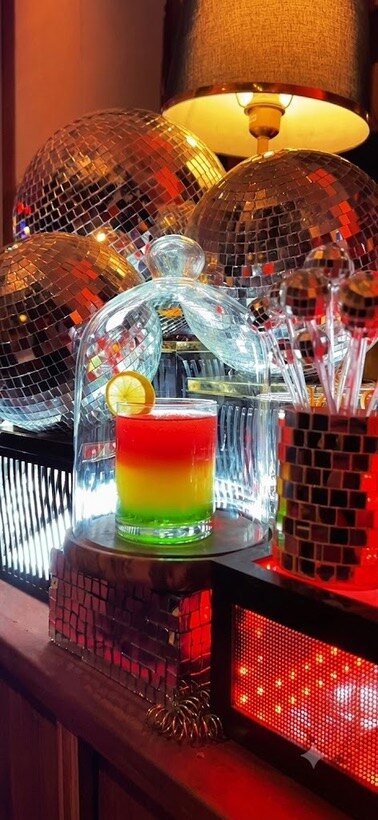 Disco-lit cocktail under a cloche